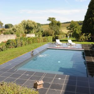 Une piscine Piscinelle installée en pleine campagne et entourée d'un beau dallage granité.